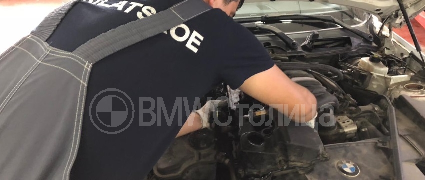 мастер устанавливает клапанную крышку на мотор БМВ